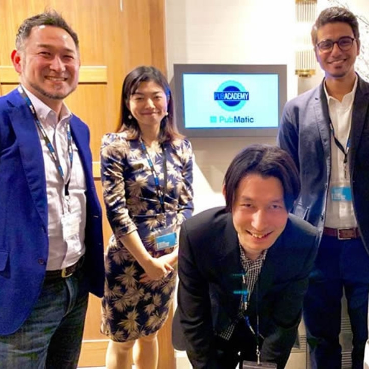 Three smiling adult men in a PubMatic office with a smiling adult woman next to them